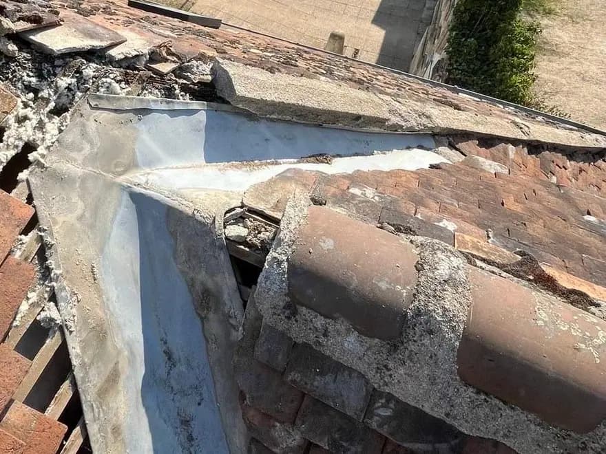 Ancienne noue métallique fissurée, mortier éclaté, tuiles plates déposées et isolant à nu